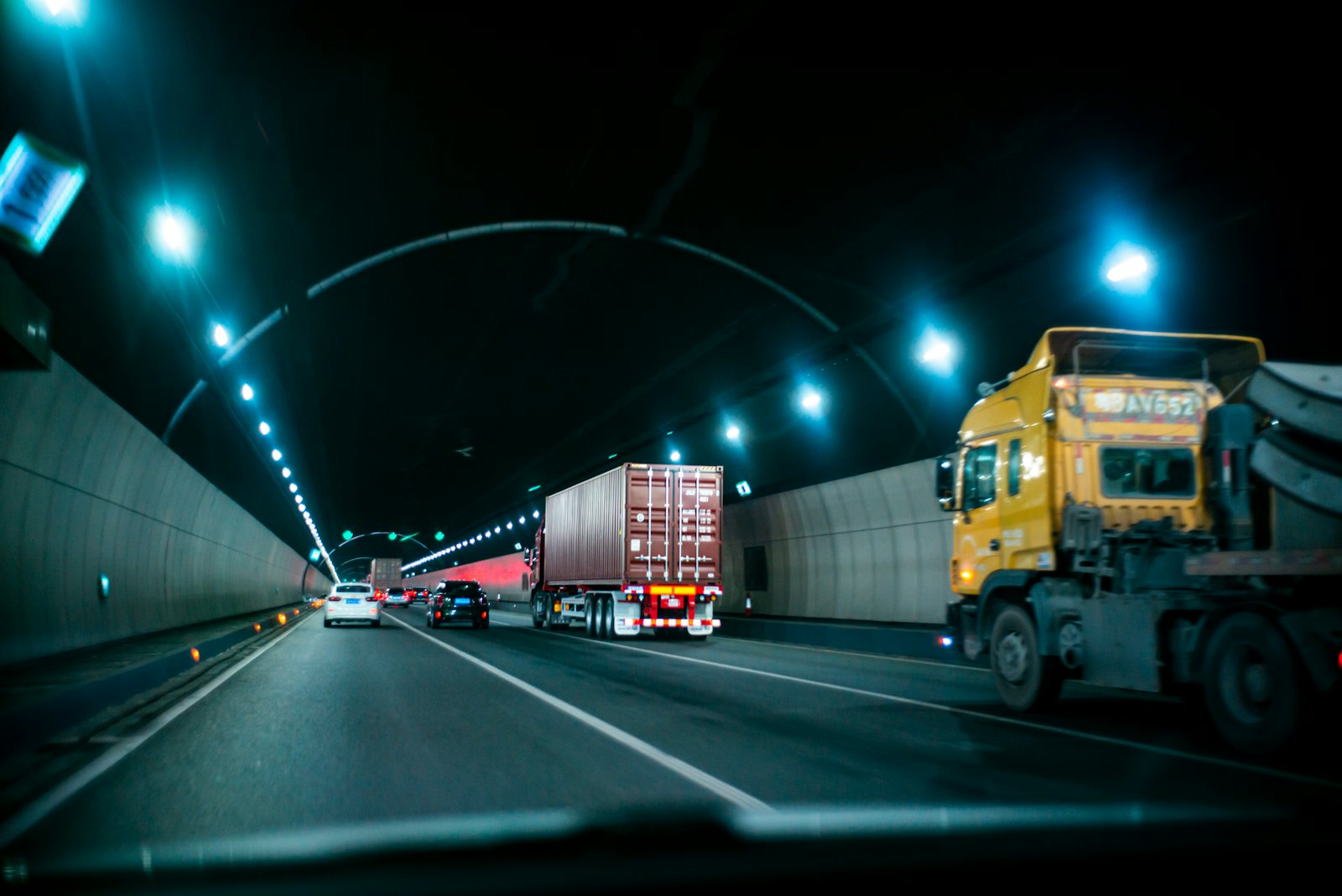 Trucks driving through a lit tunnel at night
